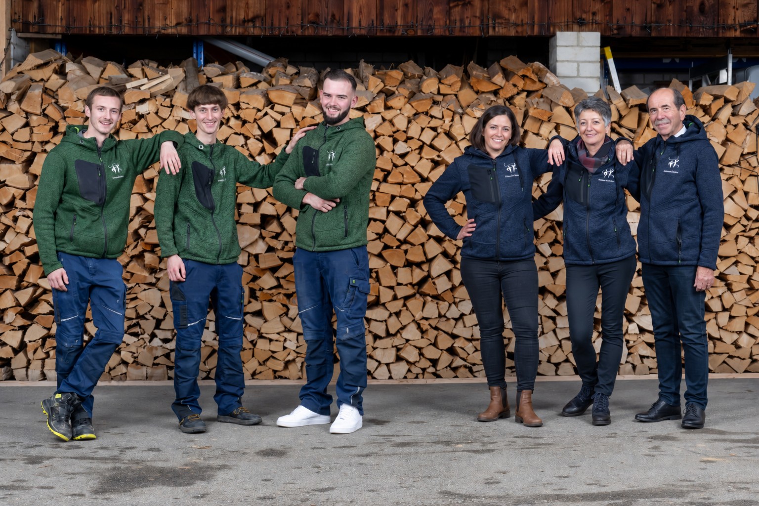 Das gesamte Team von Armonia Gärten vor einem Holzstapel